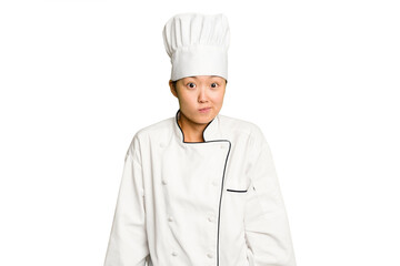 Young asian cook woman isolated shrugs shoulders and open eyes confused.