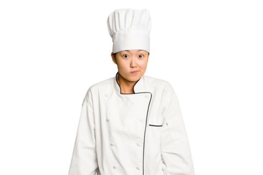 Young asian cook woman isolated shrugs shoulders and open eyes confused.
