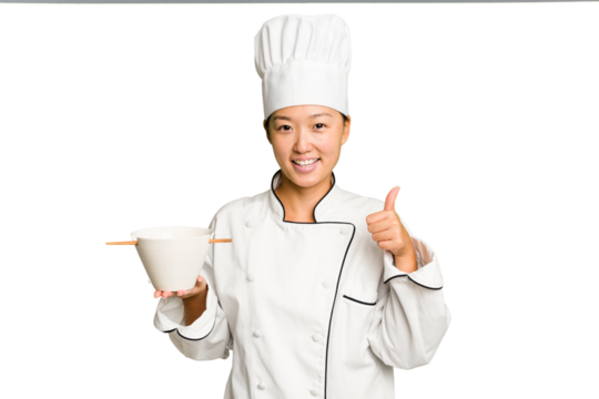 Young chef asian woman holding a bowl of ramen isolated smiling and raising thumb up