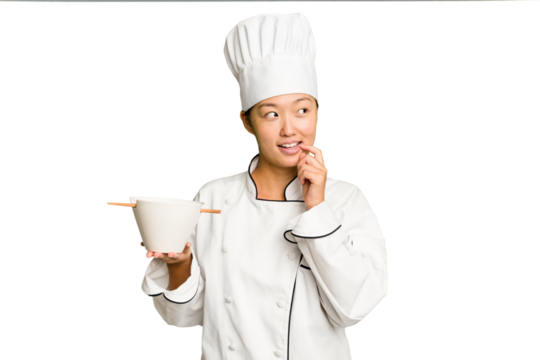 Young chef asian woman holding a bowl of ramen isolated relaxed thinking about something looking at a copy space.