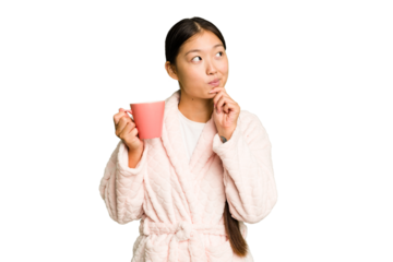 Young asian woman wearing a pajama holding a cup isolated looking sideways with doubtful and skeptical expression.