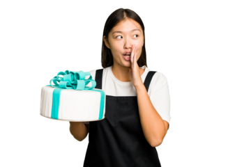 Young asian bakery holding a birthday cake isolated is saying a secret hot braking news and looking aside