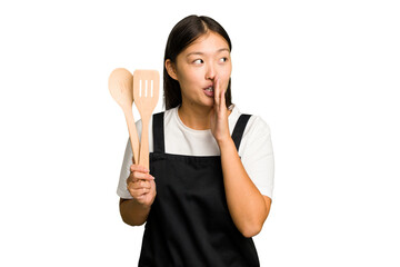 Young asian cook woman isolated is saying a secret hot braking news and looking aside