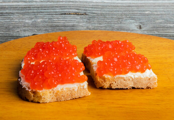 A red caviar sandwich on a plate on a white table