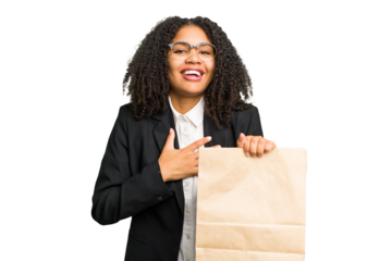 Young african american business woman holding a take away bag isolated laughs out loudly keeping hand on chest.