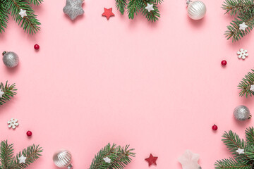 Christmas frame on pink background. Composition made of fir tree, Christmas ornament, red berries....