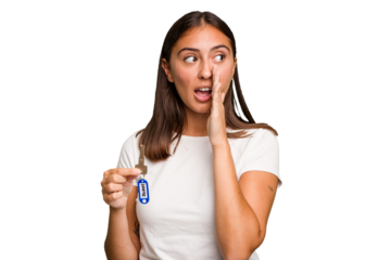 Young caucasian woman holding a home keys isolated is saying a secret hot braking news and looking aside