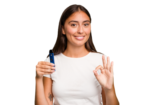 Young caucasian woman holding a electronic cigarette cheerful and confident showing ok gesture.