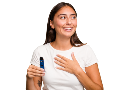 Young caucasian woman holding a electronic cigarette laughs out loudly keeping hand on chest.