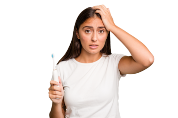 Young caucasian woman holding an electric toothbrush isolated being shocked, she has remembered important meeting.