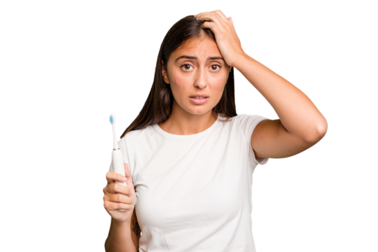 Young caucasian woman holding an electric toothbrush isolated being shocked, she has remembered important meeting.