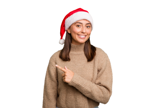 Young caucasian woman celebrating christmas wearing a santa hat isolated smiling and pointing aside, showing something at blank space.