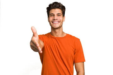 Young caucasian handsome man isolated stretching hand at camera in greeting gesture. © Asier