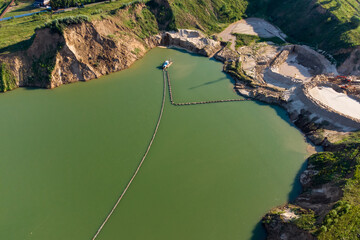 Sand mining in a flooded sand pit with a floating dredger, aerial view