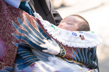 お宮参り(初宮詣)のお祝いでおじいちゃんに抱かれる赤ちゃん