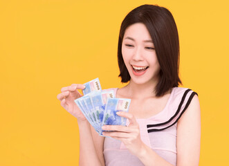 happy young counting money and isolated on yellow background - obrazy, fototapety, plakaty