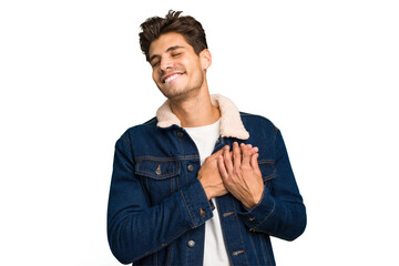 Young caucasian handsome man isolated has friendly expression, pressing palm to chest. Love concept.