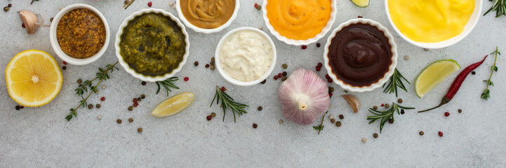 Different types of sauces in bowls with seasonings banner, rosemary and pepper, thyme and garlic, lime and lemon, cilantro, top view, copy space