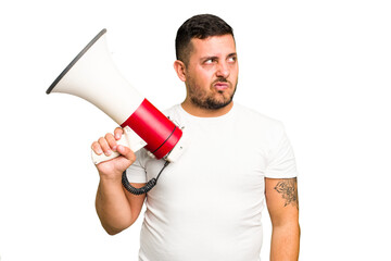 Young caucasian man holding a megaphone isolated confused, feels doubtful and unsure.