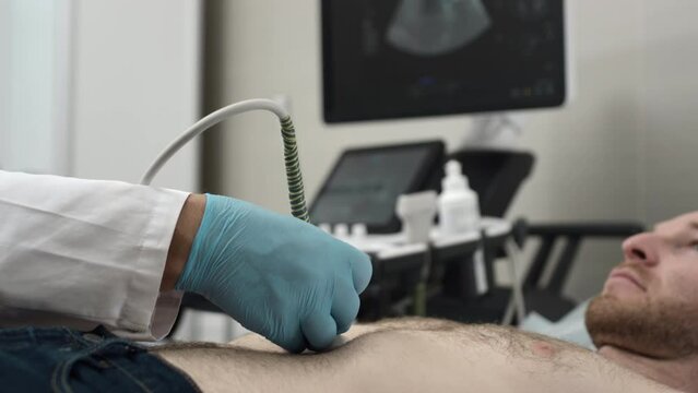 Ultrasound: A doctor checks a man's stomach with an ultrasound machine. Diagnosis of liver and pancreatic diseases. Examination of the body in the clinic office. Checking the status of sonograms