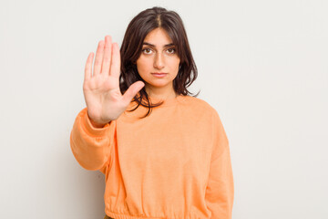 Young Indian woman isolated on white background standing with outstretched hand showing stop sign,...