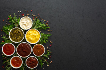 Fototapeta na wymiar Different types of sauces in bowls with seasonings, rosemary and dill, thyme and and peppercorns, top view, copy space