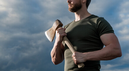 cropped view of strong man with axe. caucasian man hold ax. brutal man on sky background