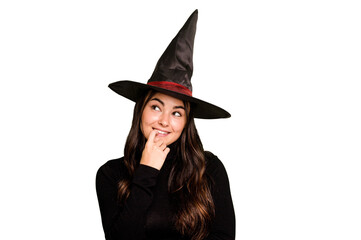 Fototapeta premium Young caucasian woman dressed as a witch isolated on green chroma background relaxed thinking about something looking at a copy space.
