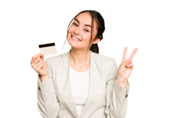 Young caucasian woman holding a credit card isolated on green chroma background joyful and carefree showing a peace symbol with fingers.