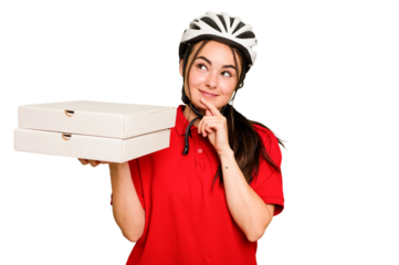 Young caucasian delivery woman holding a pizzas isolated on green chroma background looking sideways with doubtful and skeptical expression.