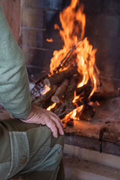 Mano de hombre apoyada en pierna, en el fondo fuego y parrilla quemándose para limpiarla y asar carne