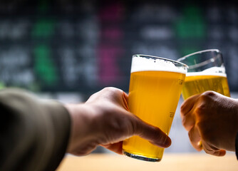 Two friends hands with glasses of craft beer at the pub or bar. taproom