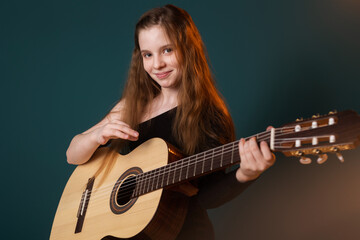 Obraz premium cute young girl playing the guitar on the background.
