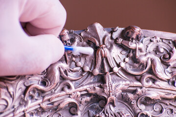 Restoration on Antique French metal plated centerpiece . Art Expert cleaning metal surface with cotton swab.