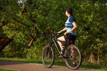 Fototapeta na wymiar Young athletic woman on a bike ride in the park