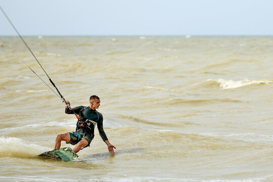 Young attractive kiteboarder rides the waves