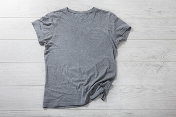 Shirt mockup - pleated, wrinkled t-shirt on white wooden desk top view - 545920994