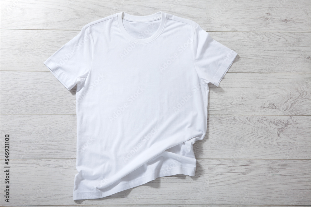 Poster white shirt mockup - pleated, wrinkled t-shirt on white wooden desk top view