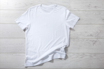 White shirt mockup - pleated, wrinkled t-shirt on white wooden desk top view