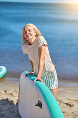 Naklejka na ściany i meble Smiling good-looking woman with a kayak on the beach