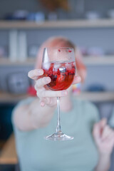 Woman holding cocktail towards camera