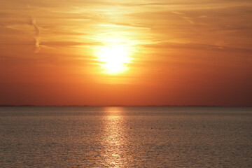 Obraz premium Horizontal photo of the sun setting in the ocean during golden hour