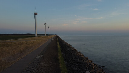 Aerial photo of wind turbines next to the sea during sunset