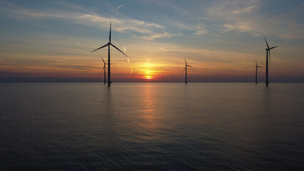 Aerial photo of wind turbines in the sea during sunset