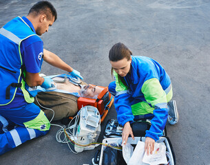 Paramedics performing CPR with mobile defibrillator for victim man lying in stretcher outside....