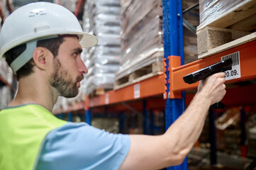 Young man in a protective helmet working in a warehouse