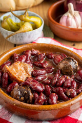 Close-up of red bean stew on red kitchen towel, with green chillies and garlic, selective focus, vertical, with copy space