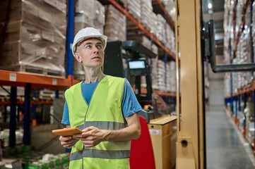 Experienced warehouse manager inspecting wares on the pallet racks