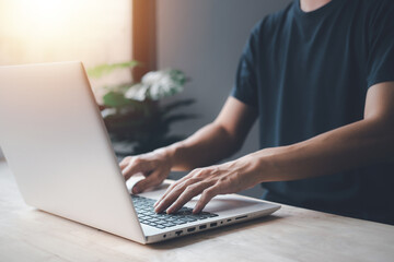 Businessman hand typing keyboard on white notebook (Laptop) at the house. Work from home concept.