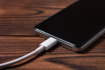 Charger battery mobile smart phone on wooden desk.